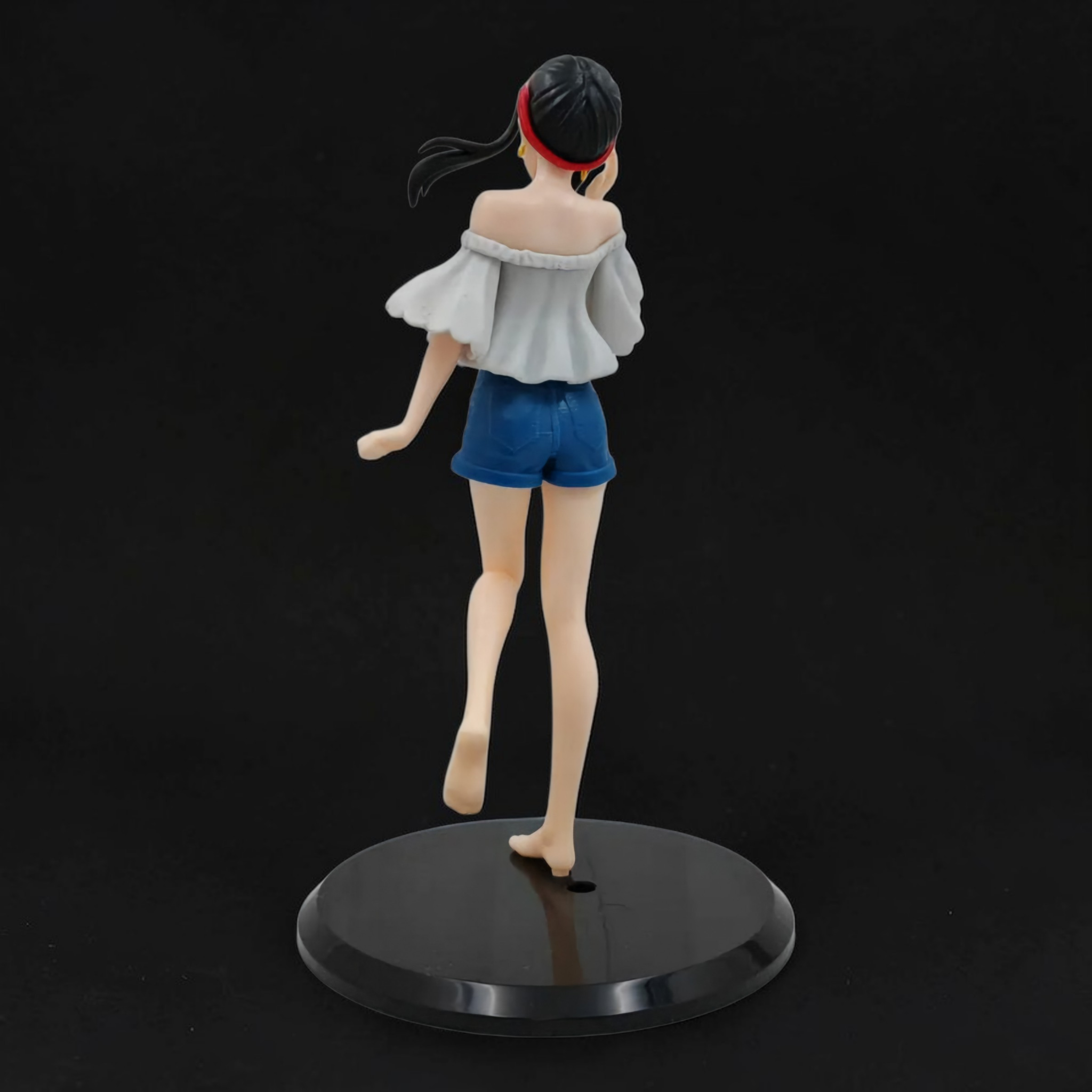 Figurine of a character with a black cap and blue shorts on a black base against a black background