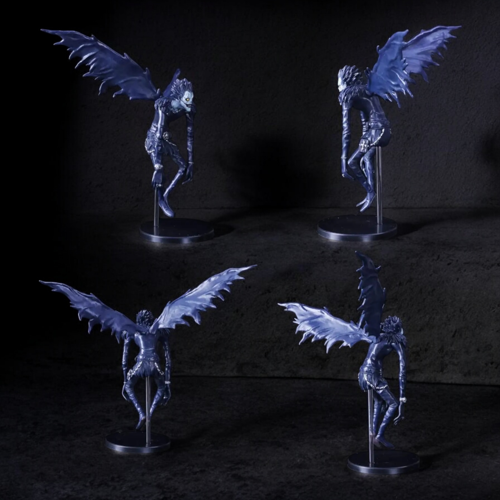 Four fantasy winged creature figurines on stands against a dark background