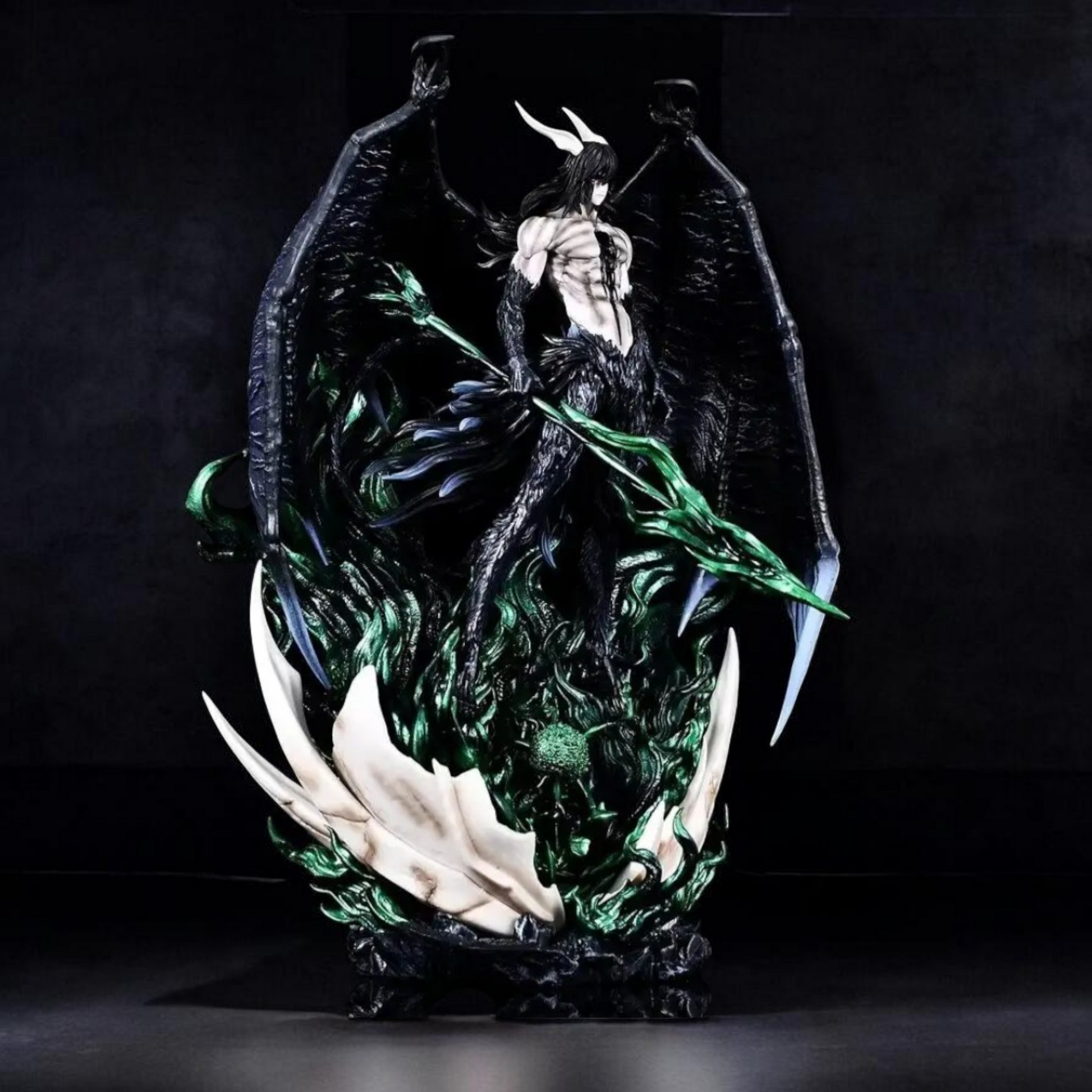 Statue of a winged creature with green accents on a dark background