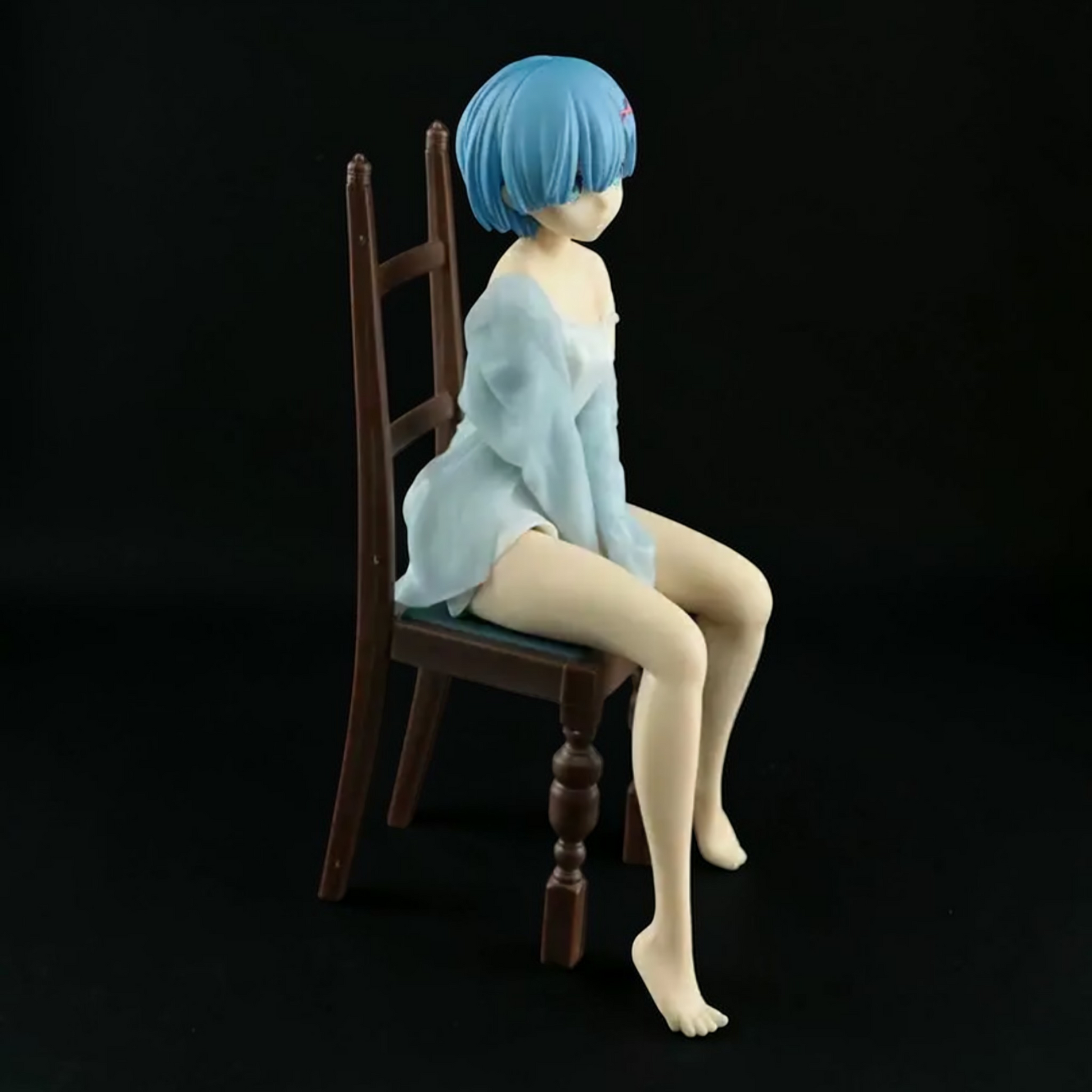 Figure of a character with blue hair sitting on a wooden chair against a black background