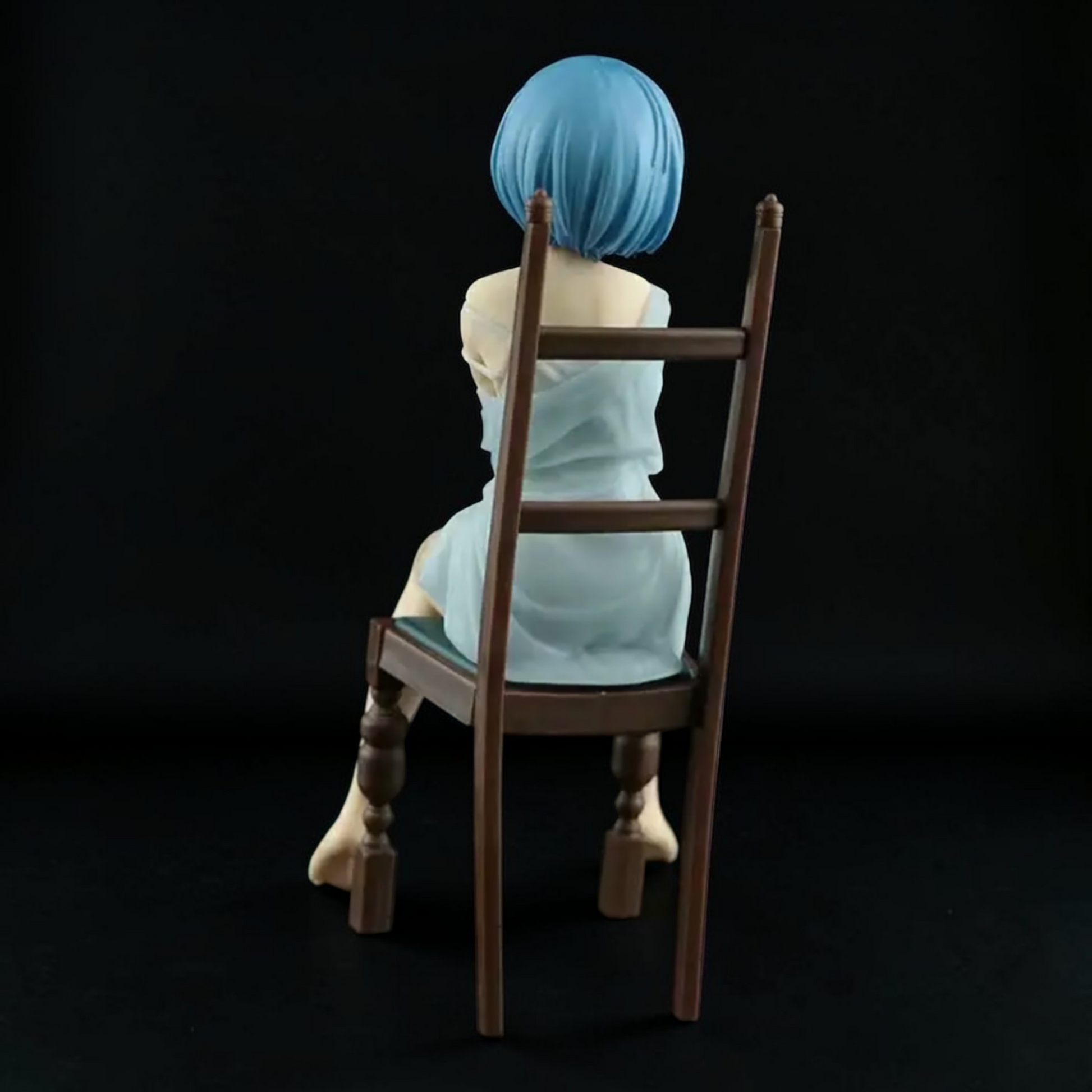 Figure with blue hair sitting on a wooden chair against a black background
