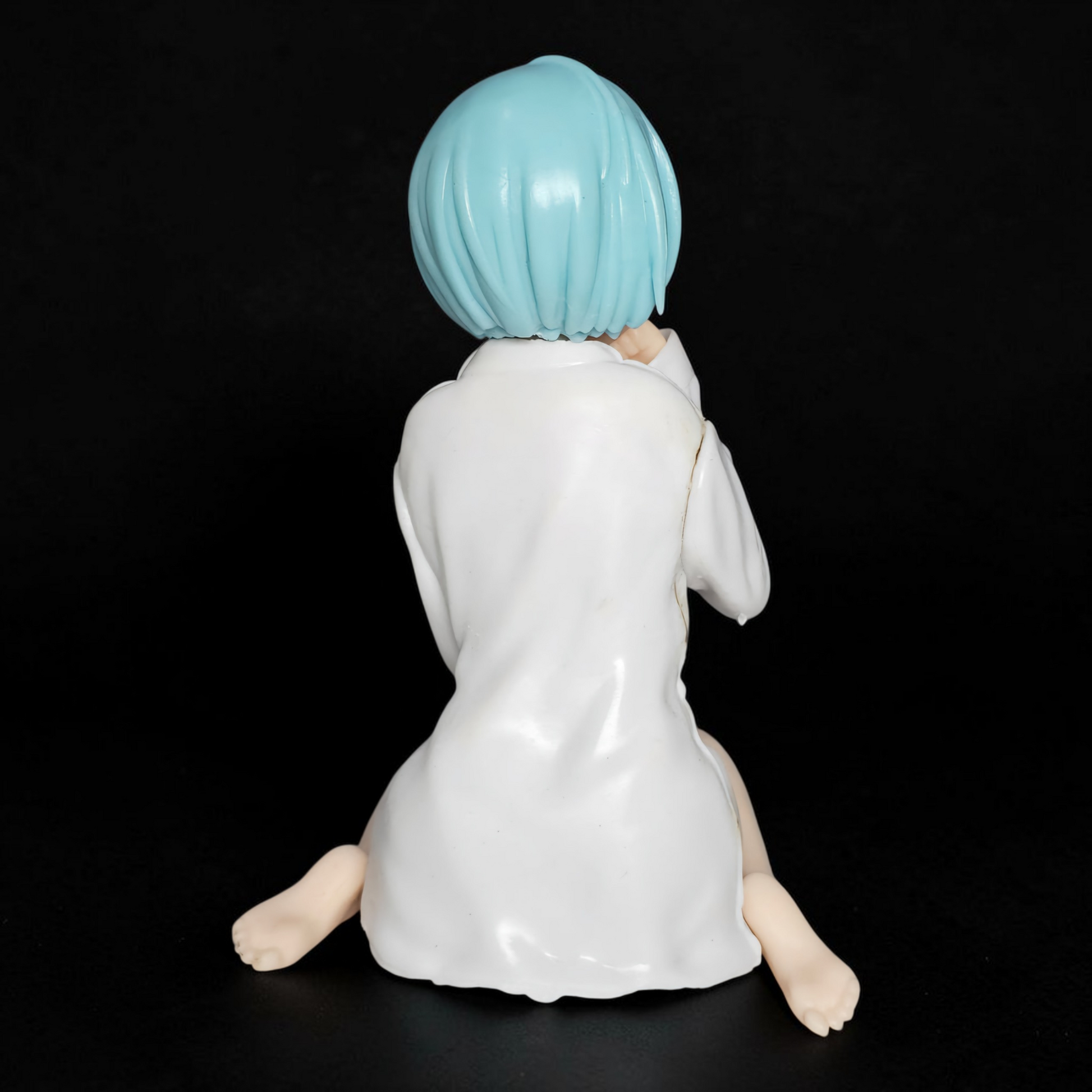 Figurine with blue hair and white outfit on a black background