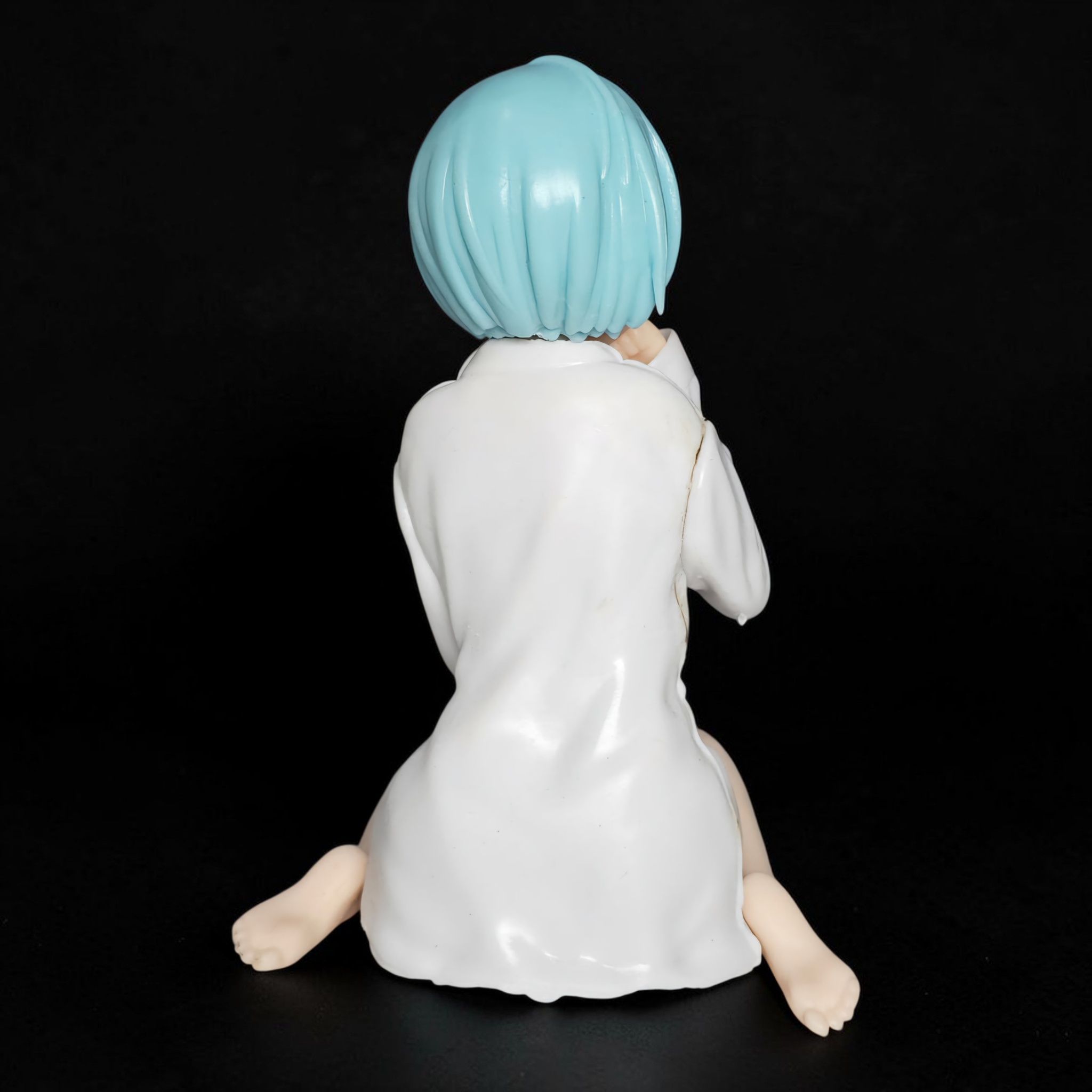 Figurine with blue hair and white outfit on a black background