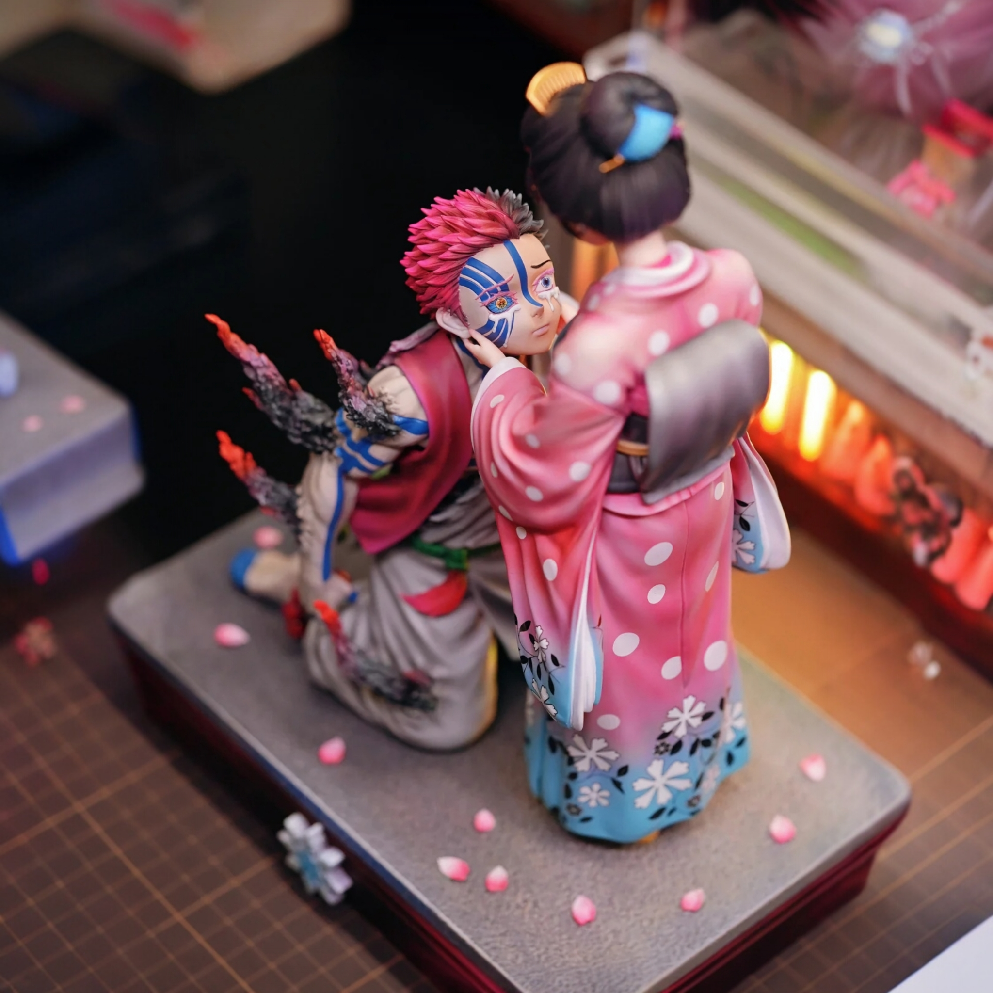 Two anime-style figurines on a gray base with a blurred background