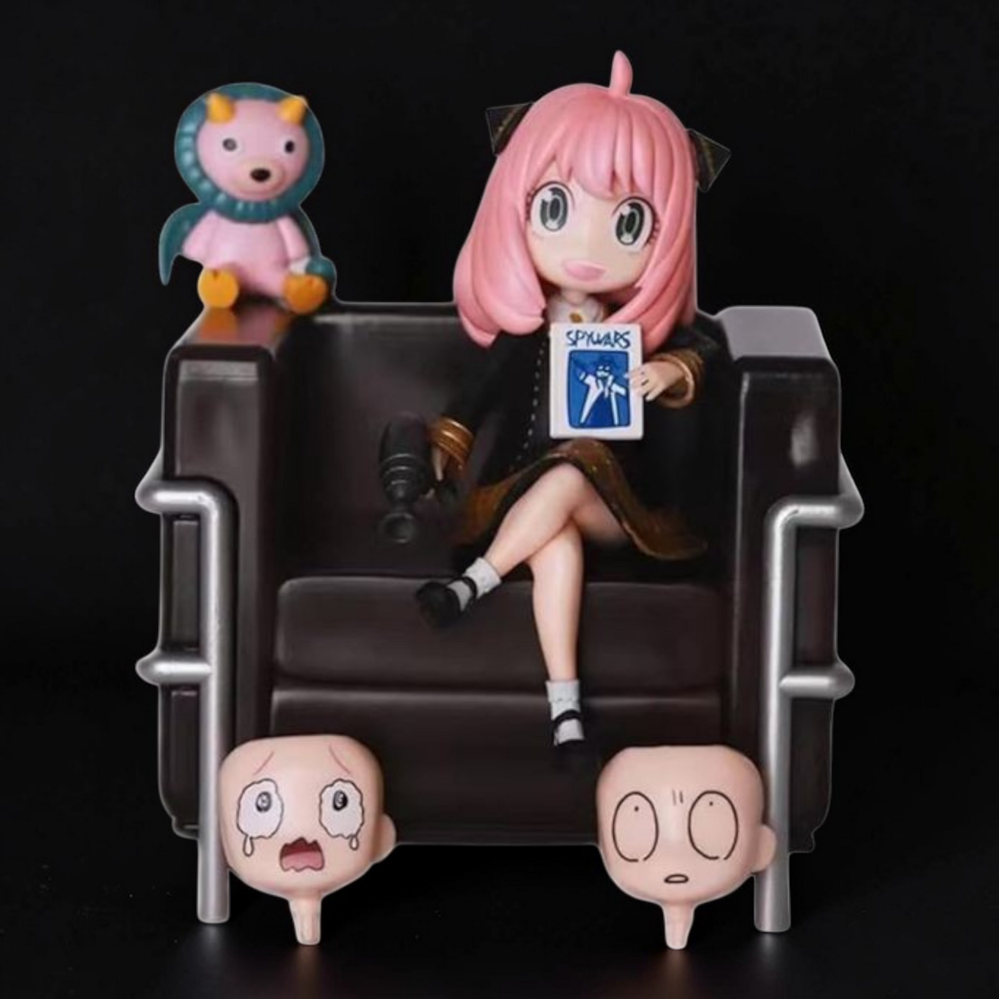Anime character figurine sitting on a chair with small figures around, against a black background