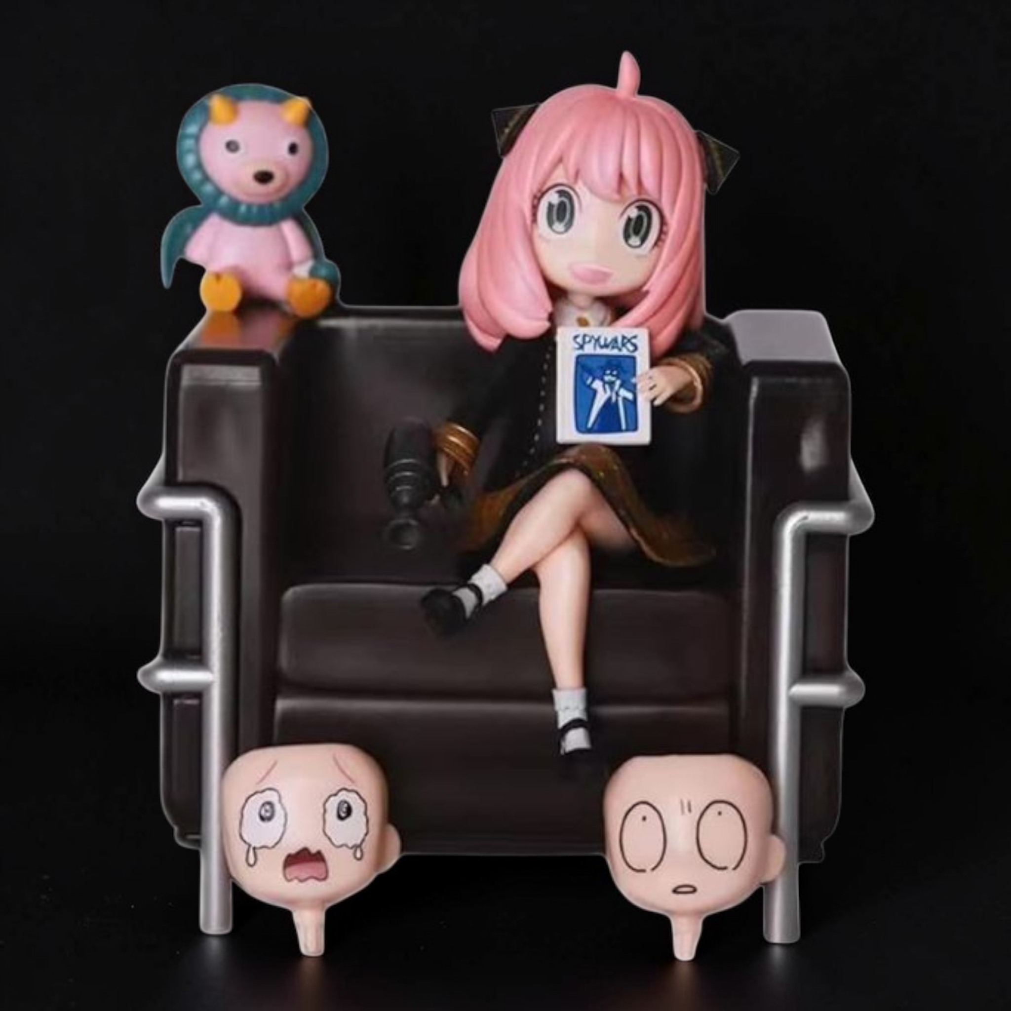 Anime character figurine sitting on a chair with small figures around, against a black background
