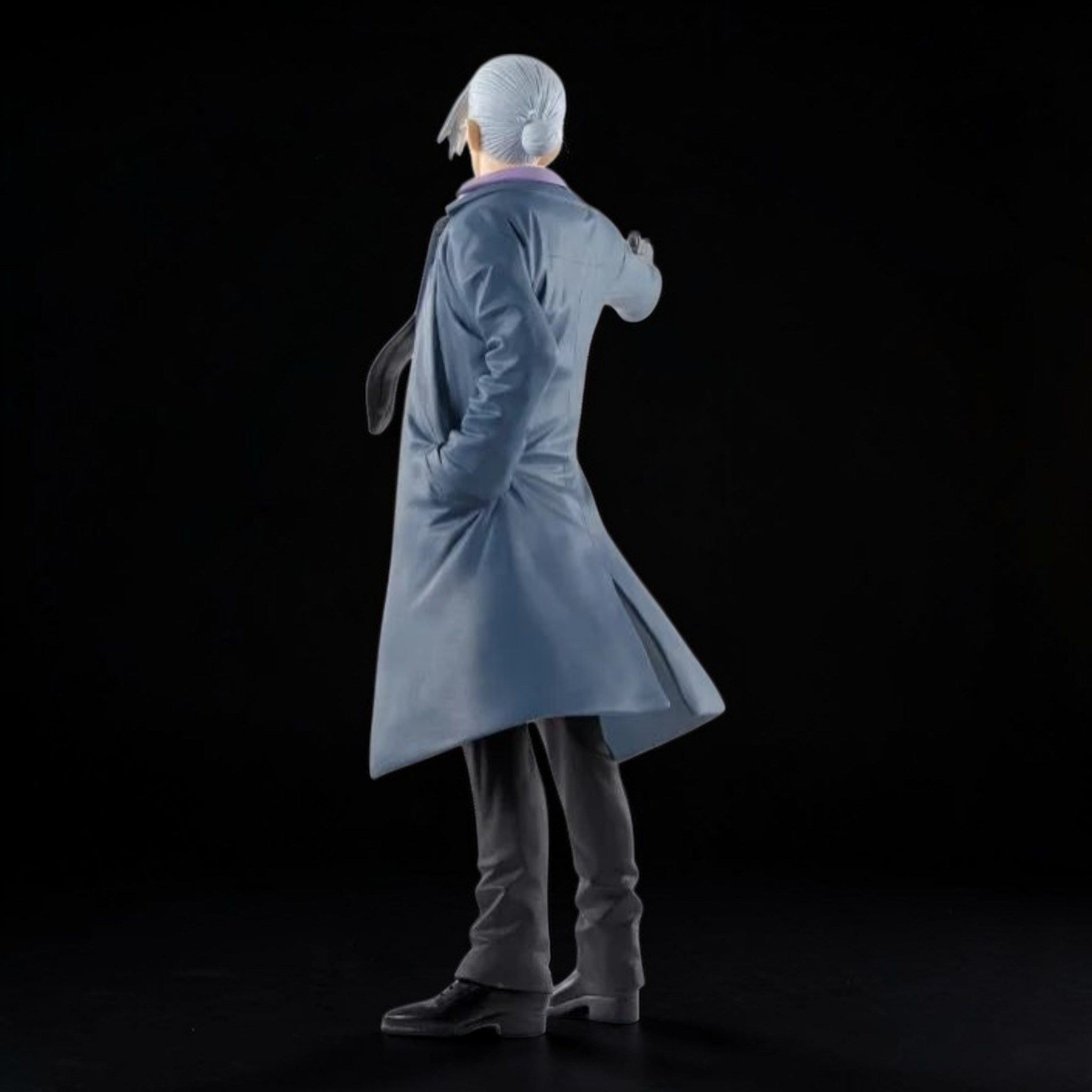 Figure of a person in a long coat and hairnet on a black background
