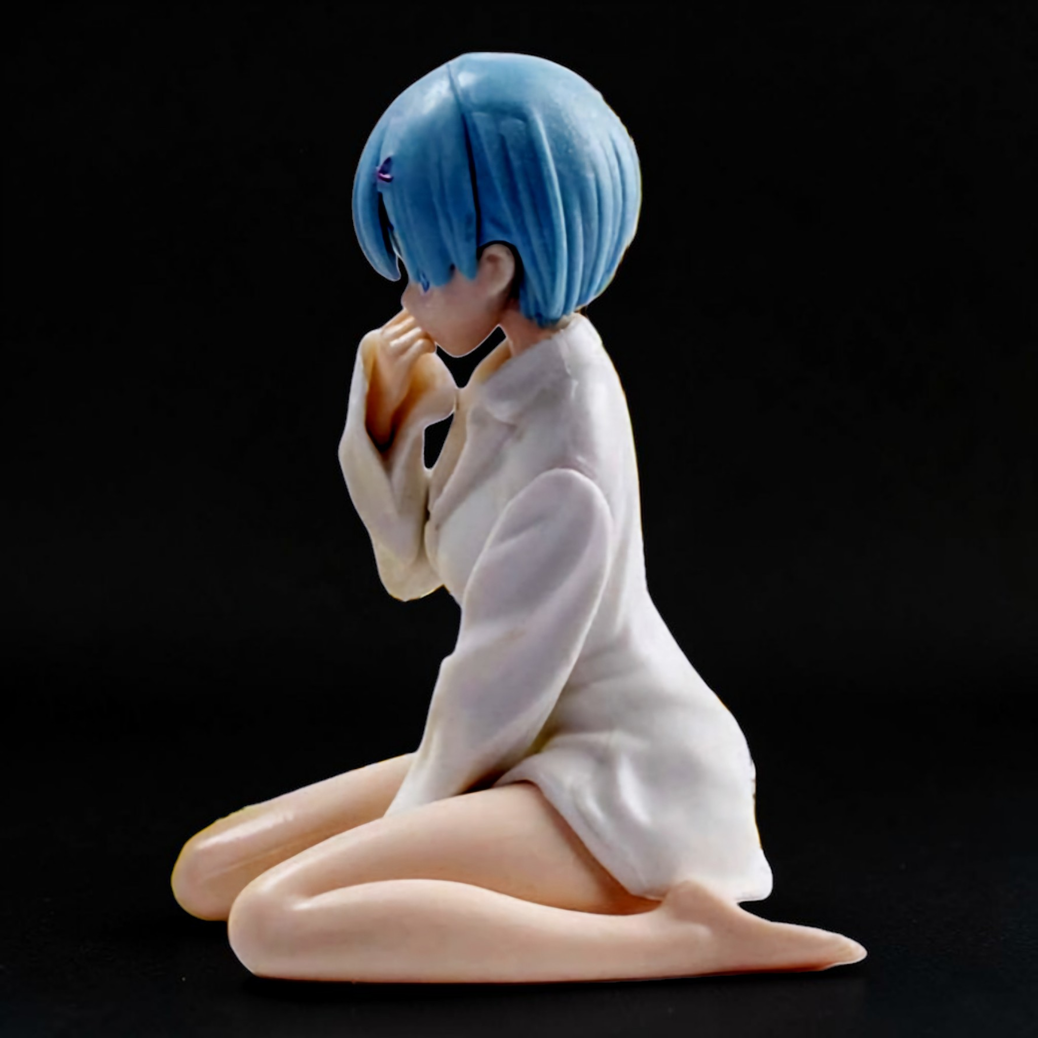 Figurine of a character with blue hair kneeling on a black background