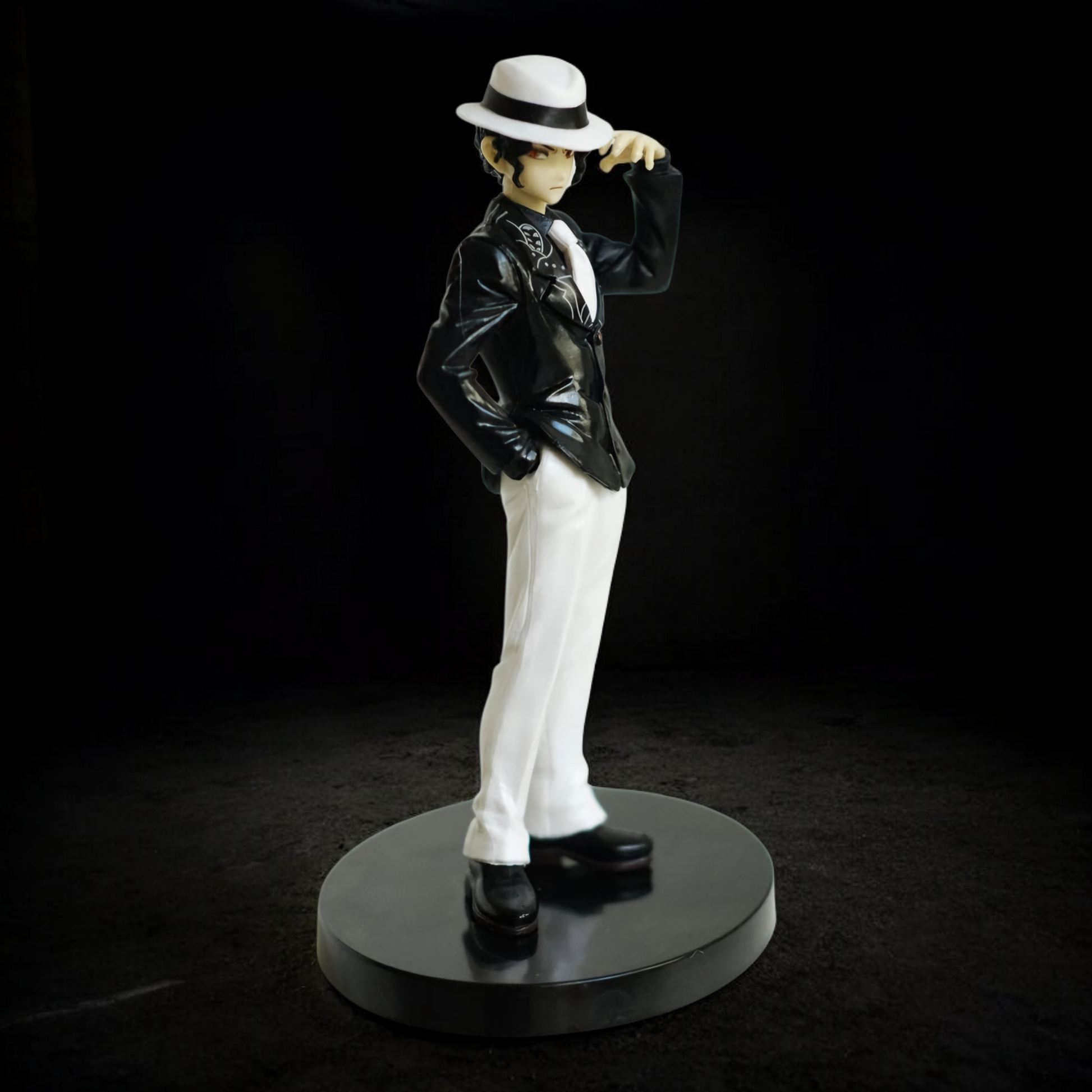 Statue of a person in formal attire with a hat on a black background