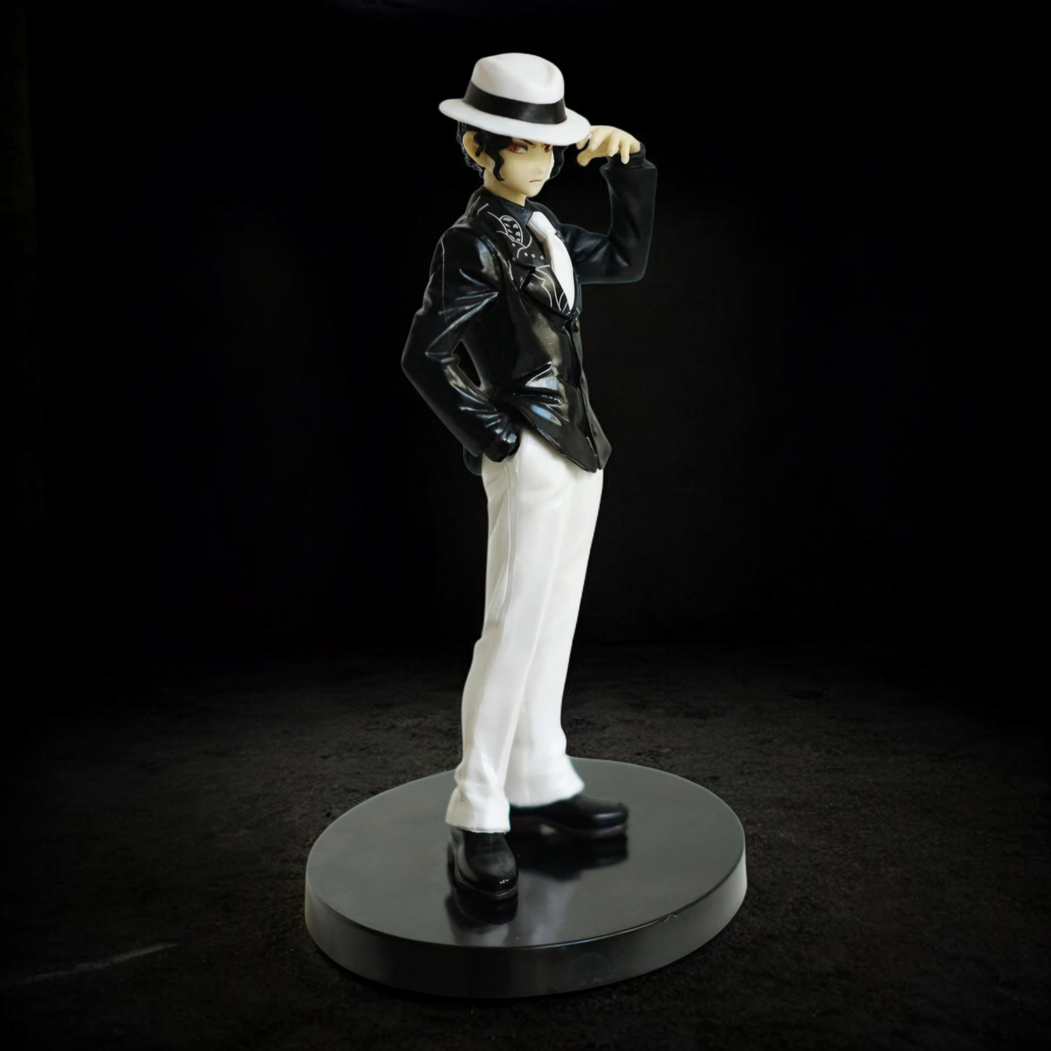 Statue of a person in formal attire with a hat on a black background