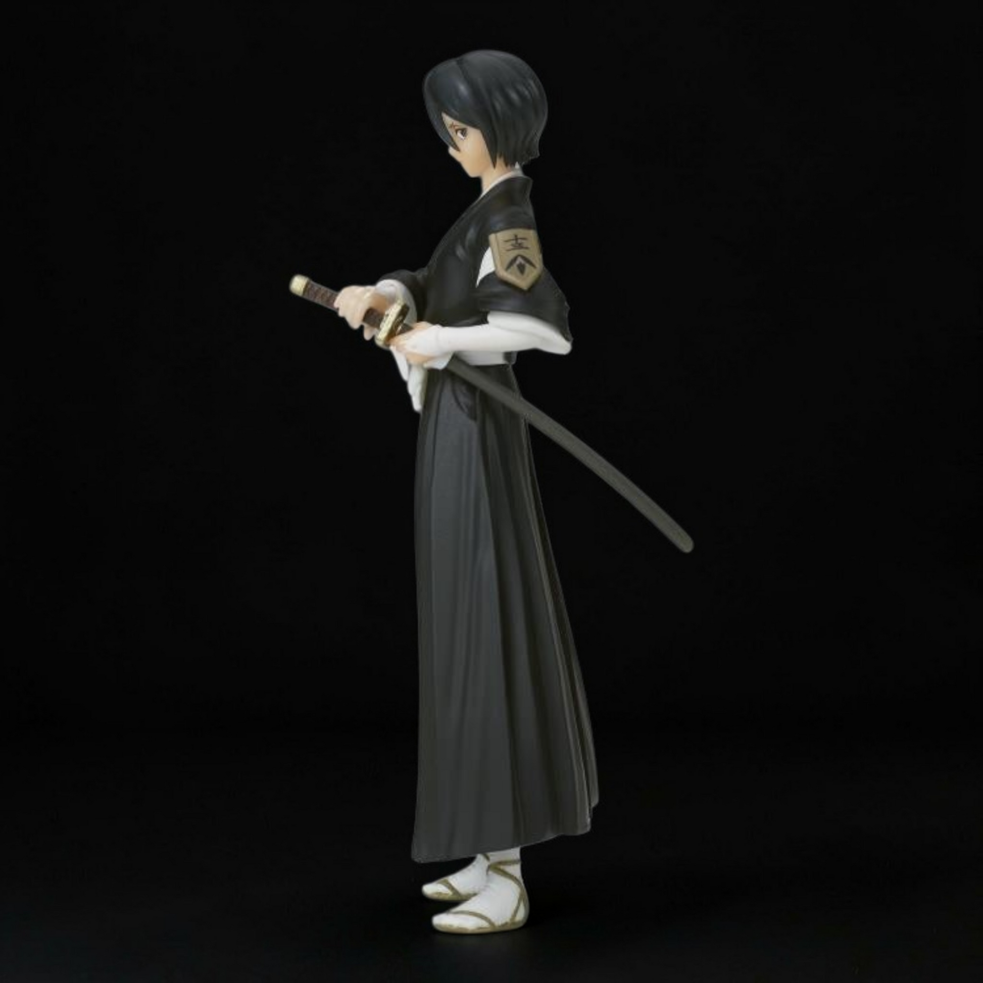 Figurine of a character in traditional attire holding a sword on a black background