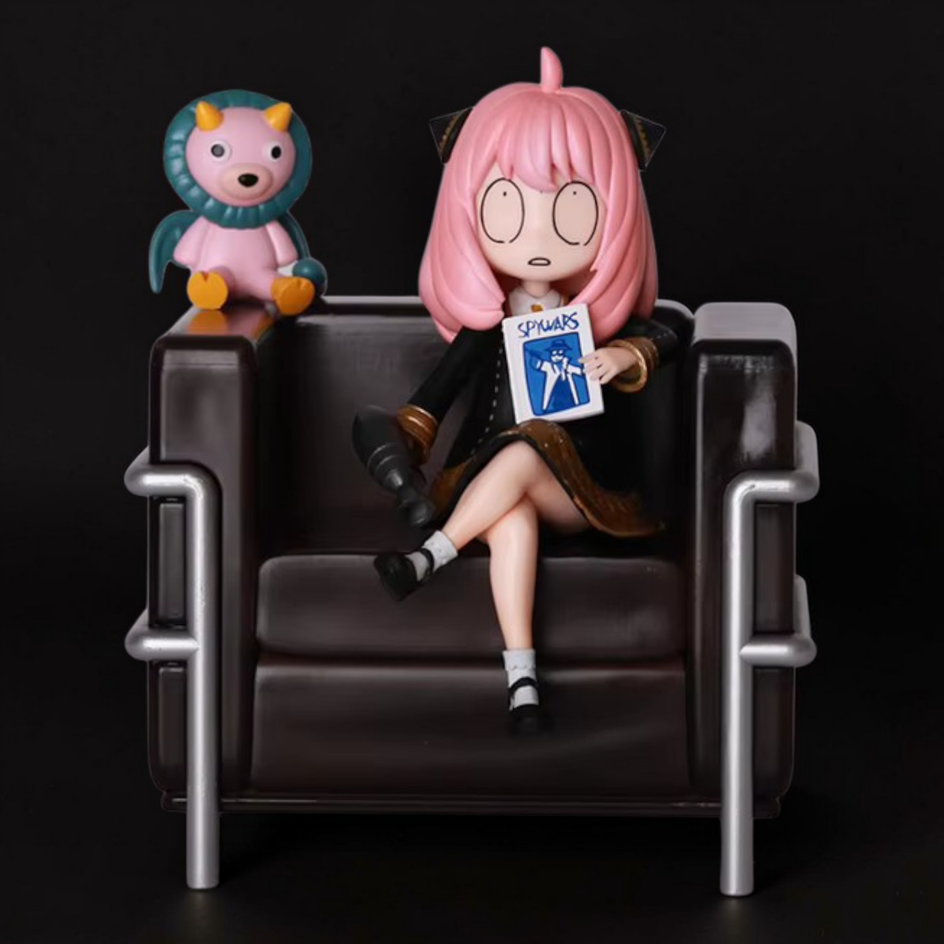 Figure of a character with pink hair sitting on a chair next to a small plush toy, against a black background.