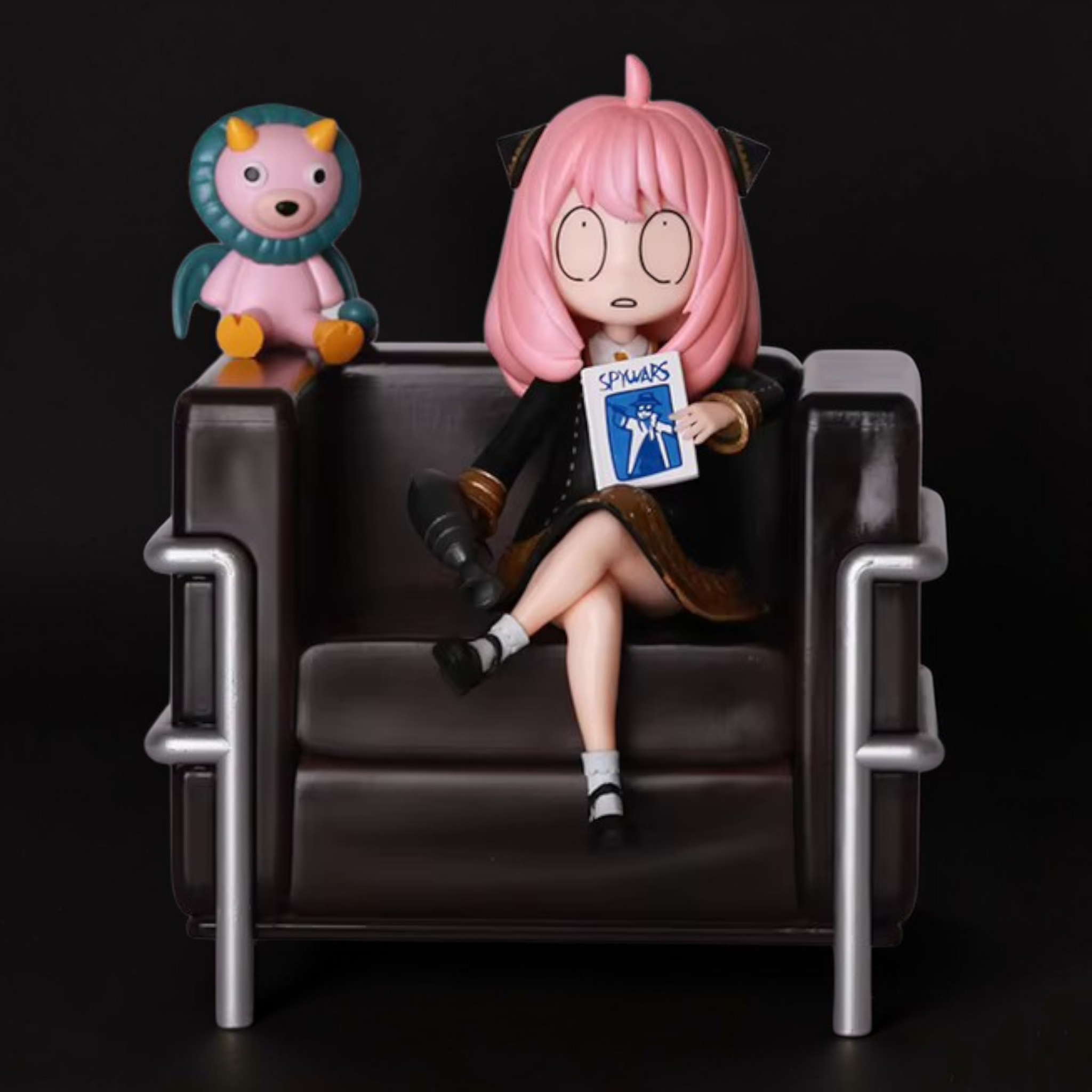 Figure of a character with pink hair sitting on a chair next to a small plush toy, against a black background.