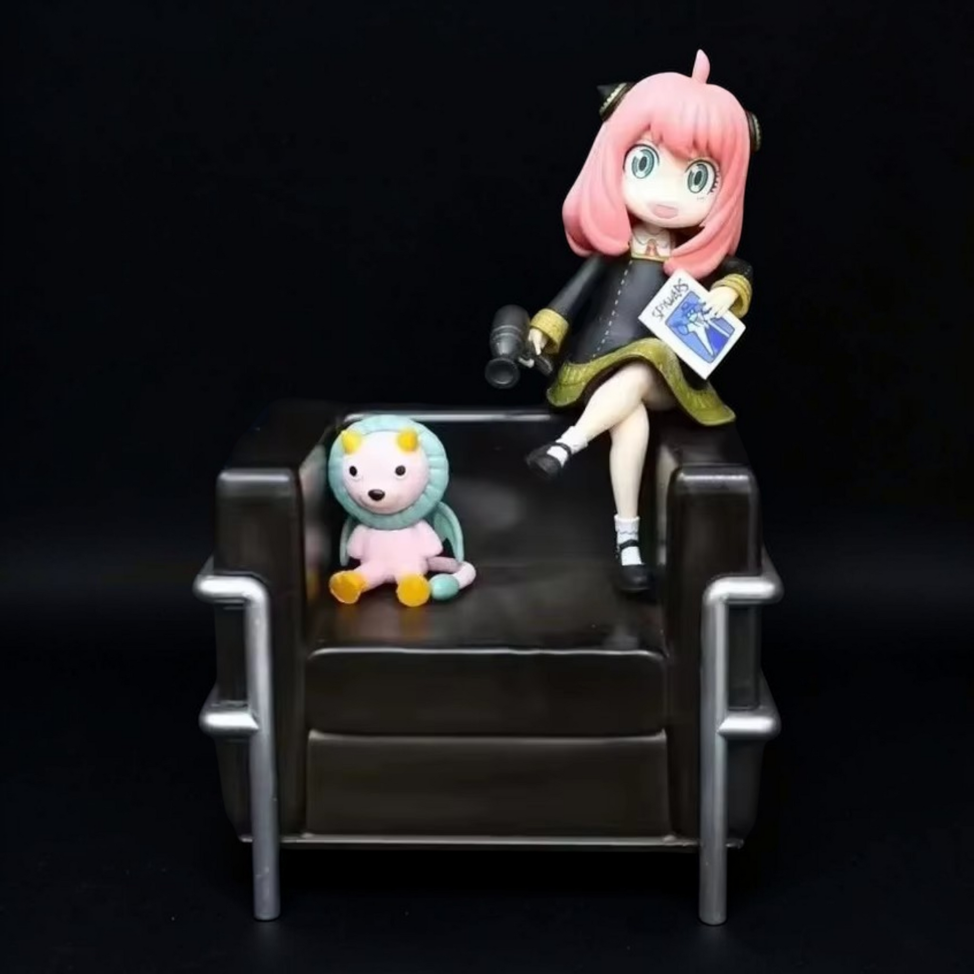 Two figurines on a black chair against a dark background