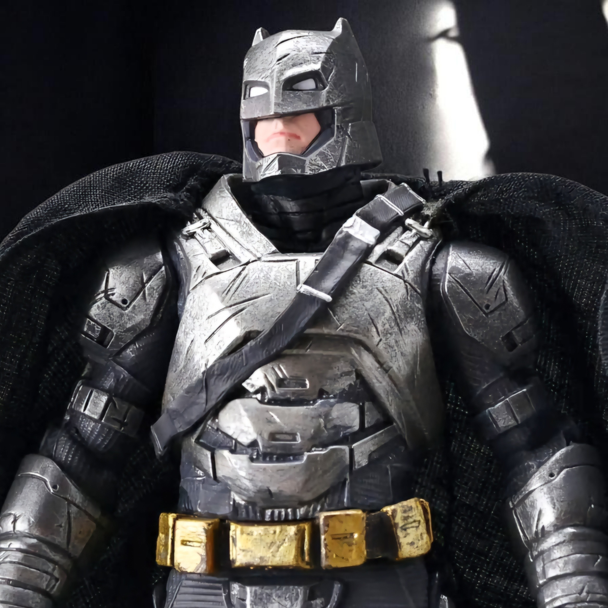 Batman action figure in detailed costume with gold accents on a dark background