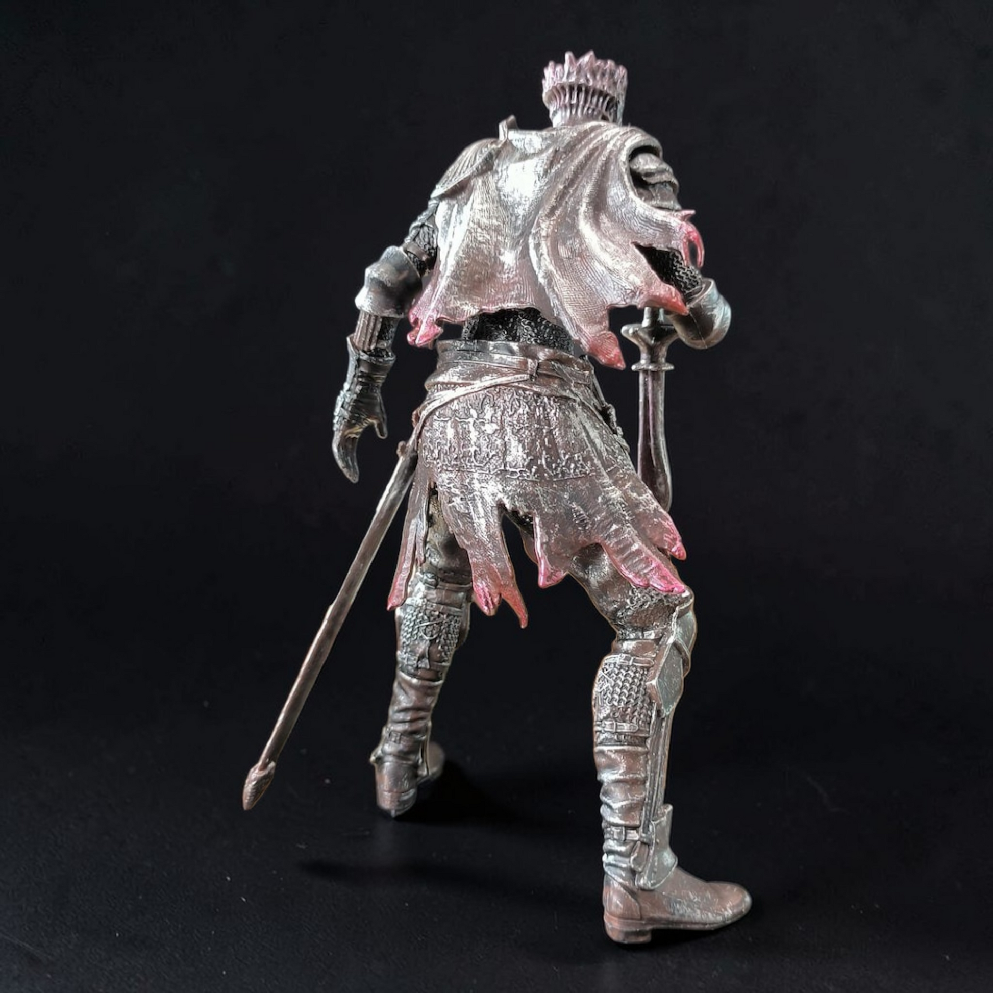 Metallic figurine of a warrior with armor and a sword on a black background