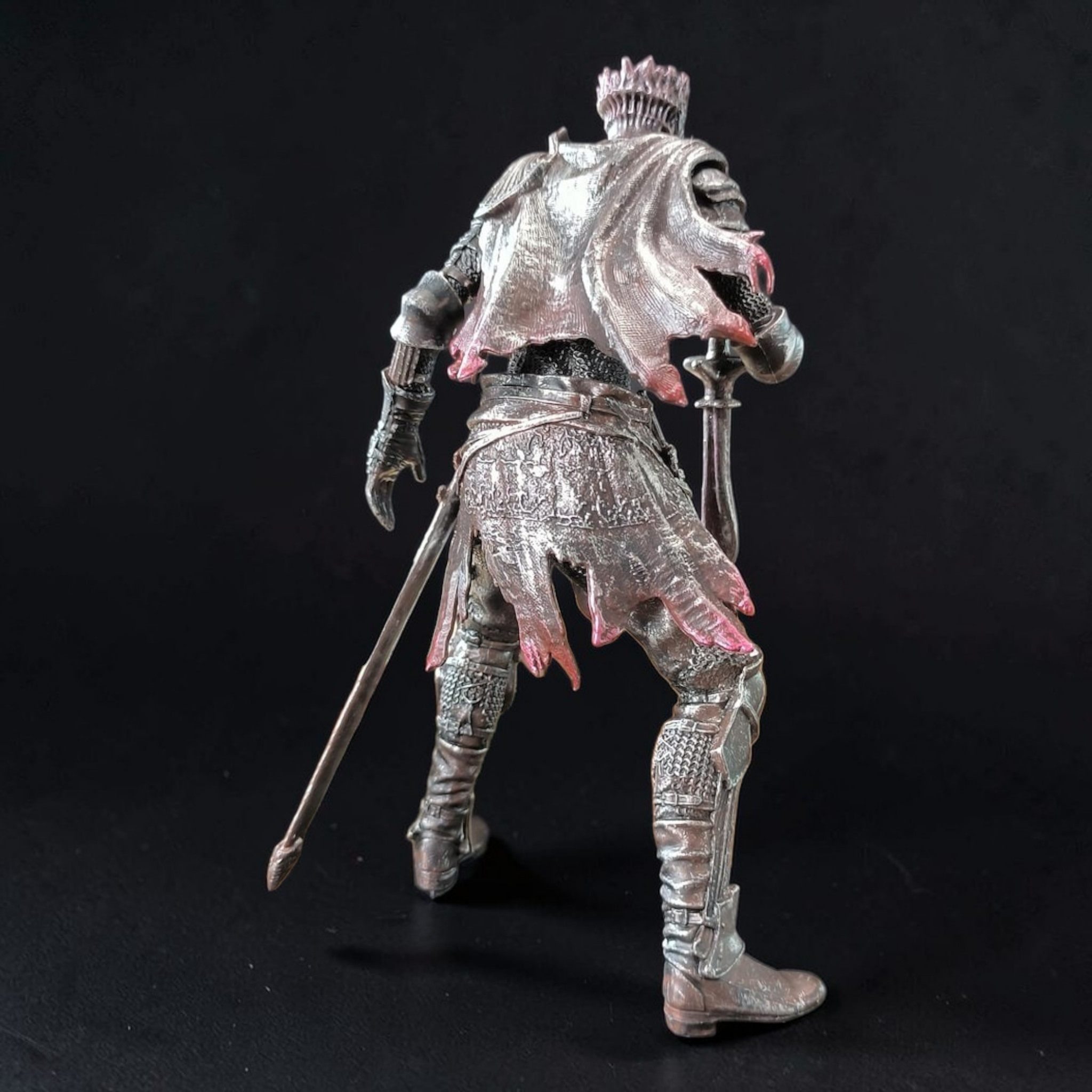 Metallic figurine of a warrior with armor and a sword on a black background