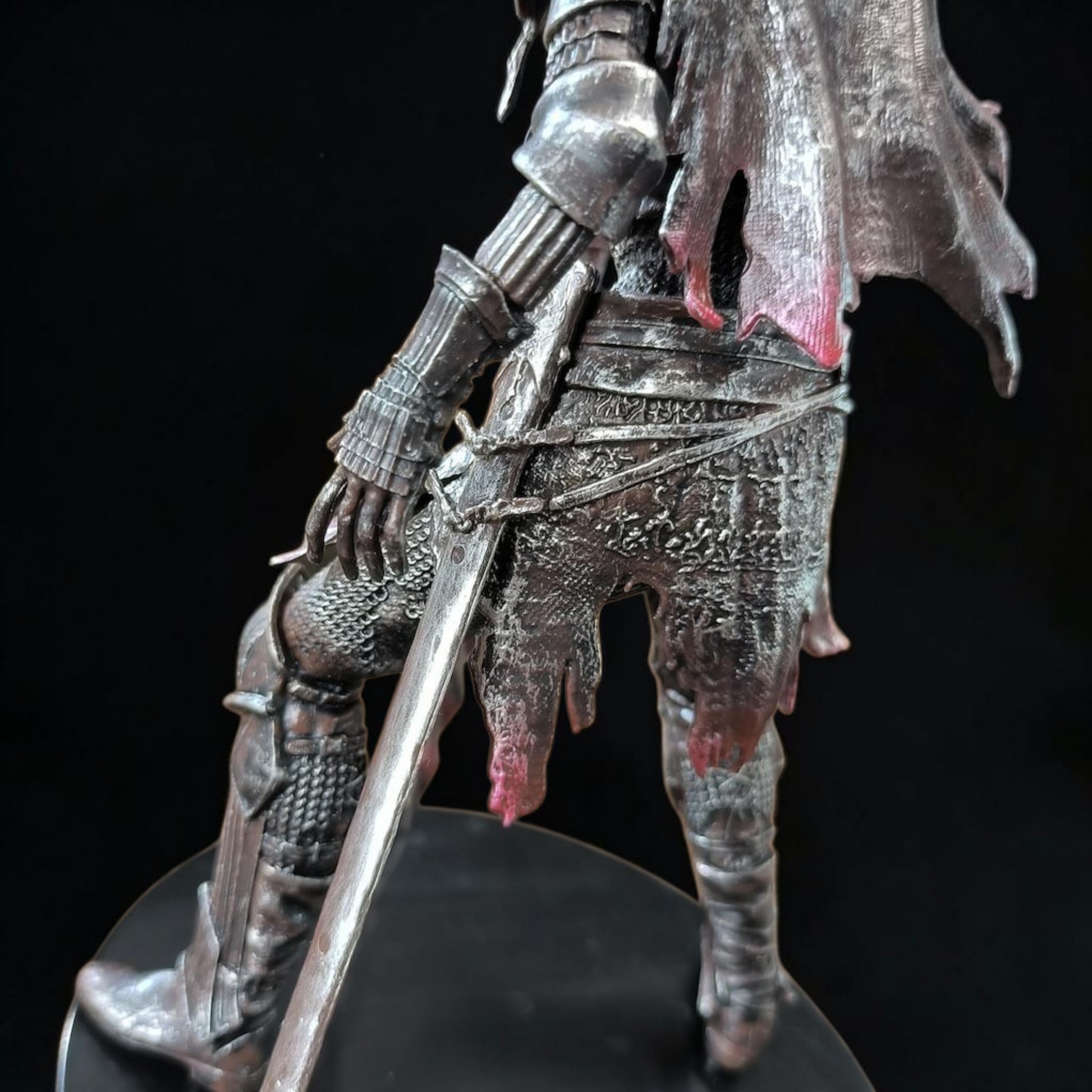Metallic figurine of a warrior with armor and a sword on a black background