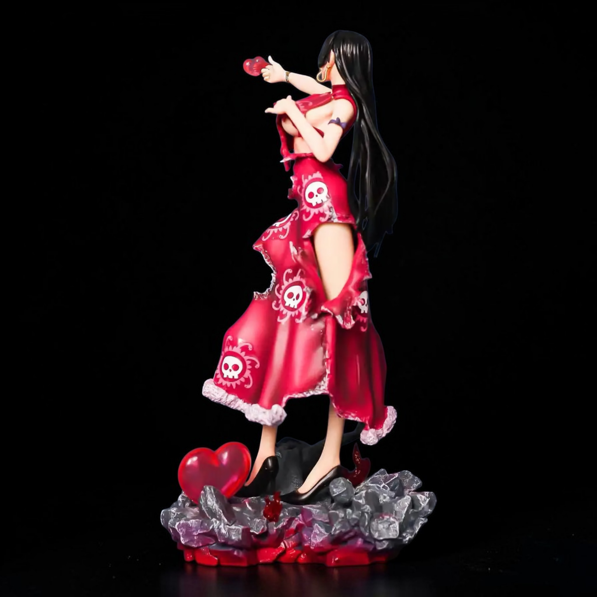 Figurine of a character in a red dress with skull designs on a black background