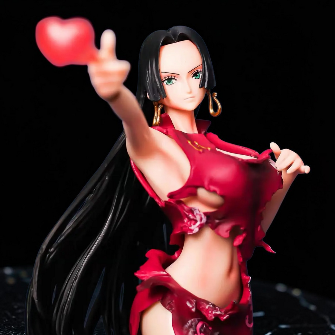 Statue of a woman in a red outfit on a tropical island with a ship and treasure chest in the background.