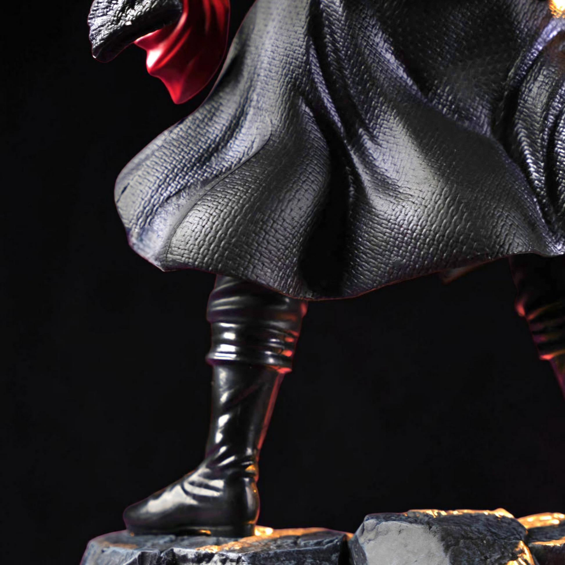 Statue of a character with a dark cloak and boots on a black background