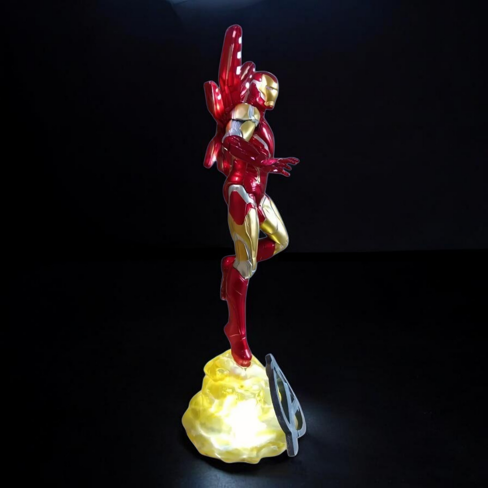 Superhero figurine on a rock with a light at its base against a black background
