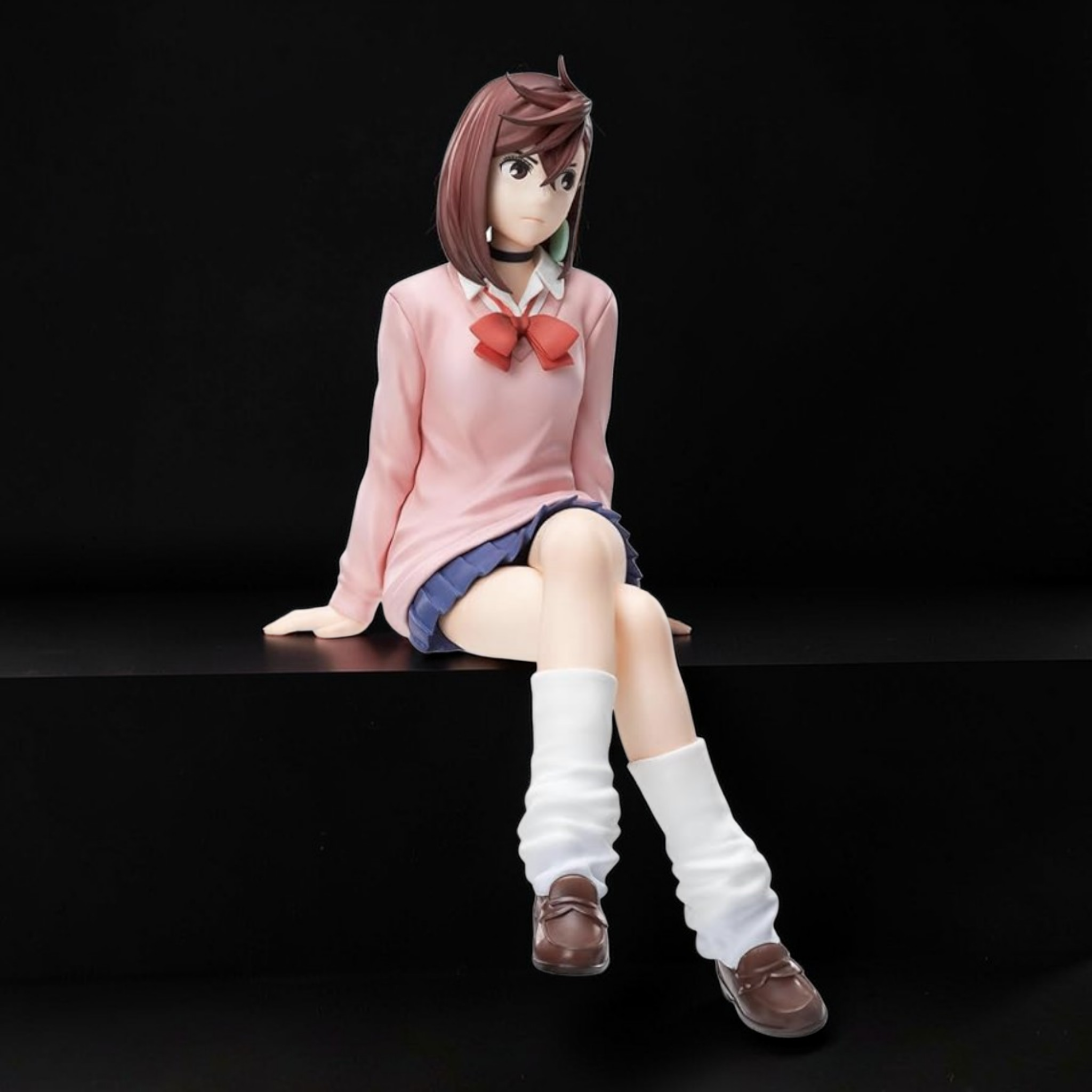 Anime character figurine sitting on a black surface with a dark background