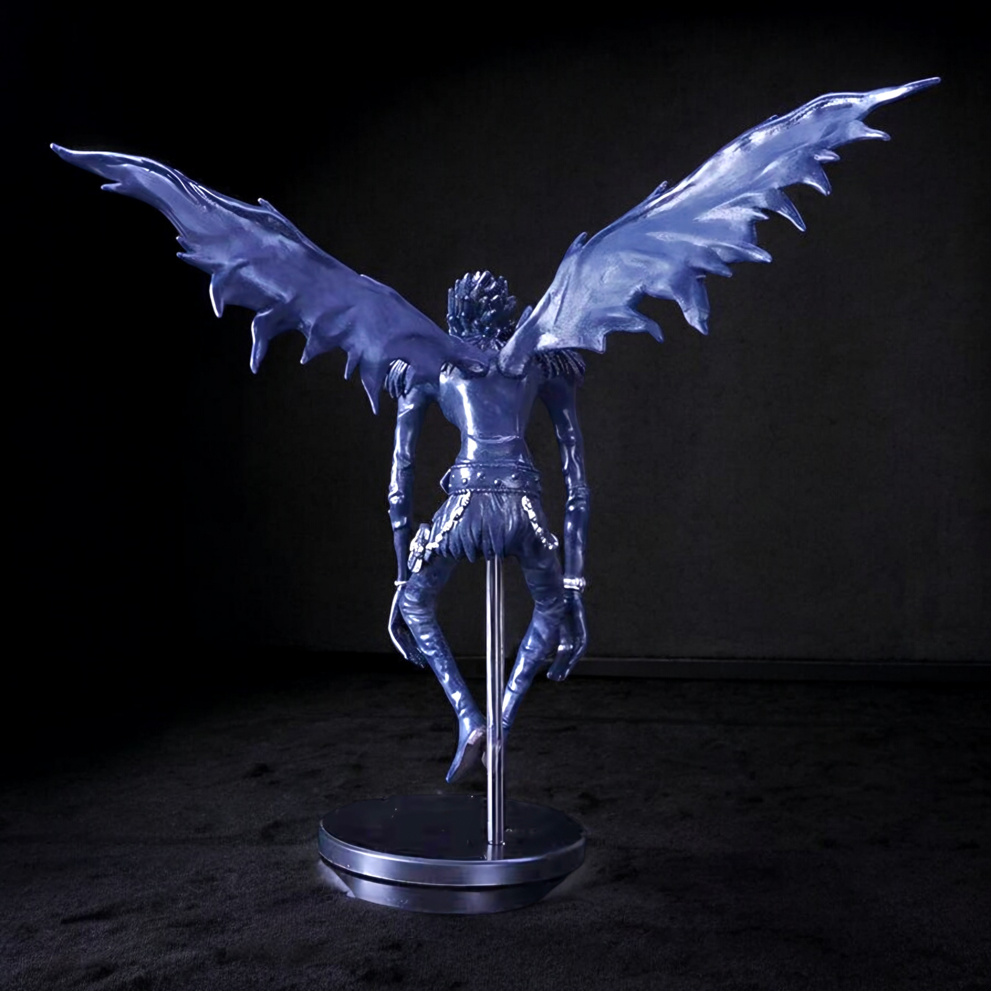 Metallic blue angel sculpture with outstretched wings on a dark background
