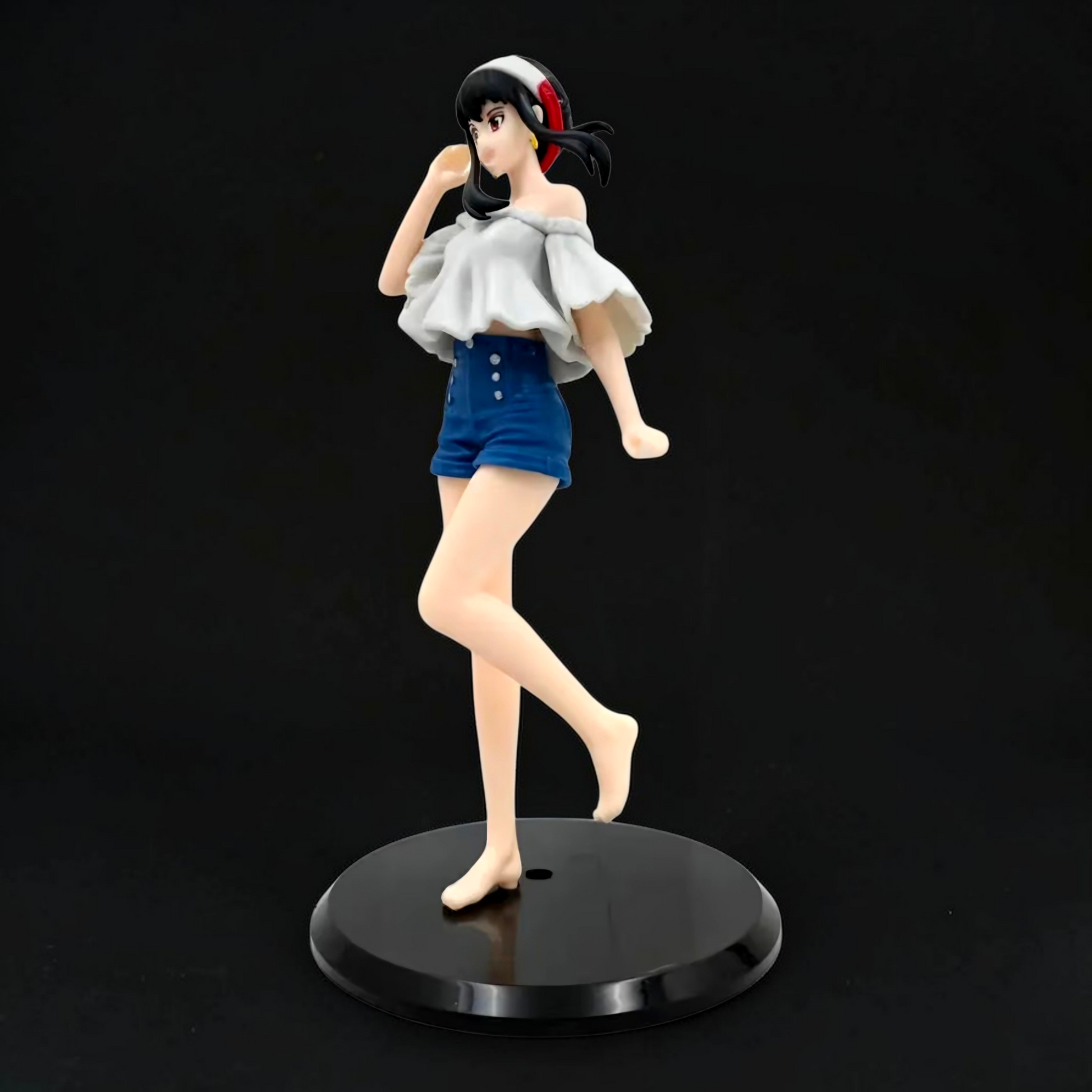 Figurine of a character in a white top and blue shorts on a black stand against a black background