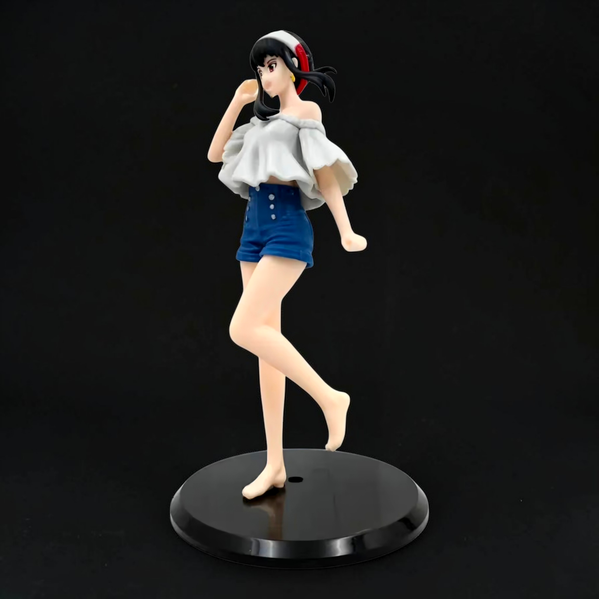 Figurine of a character in a white top and blue shorts on a black stand against a black background