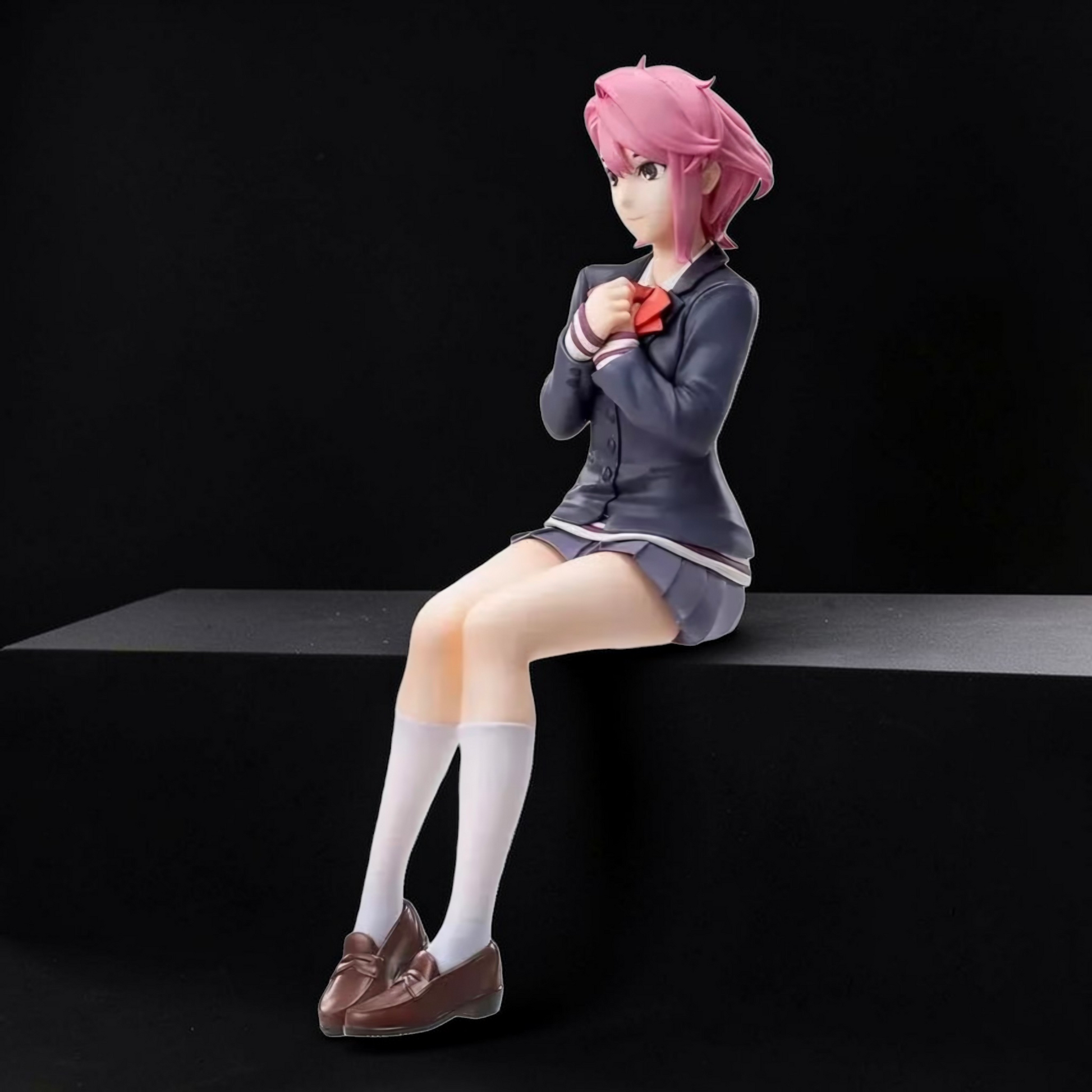 Anime character figurine with pink hair sitting on a black platform