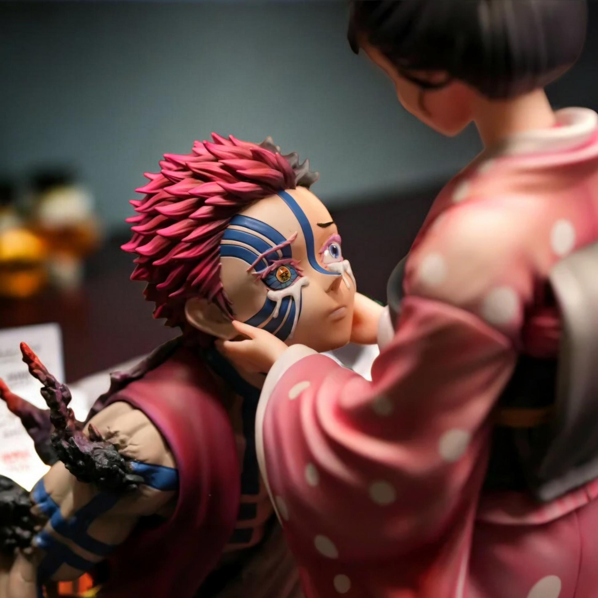 Two anime-style figurines interacting with each other on a blurred background
