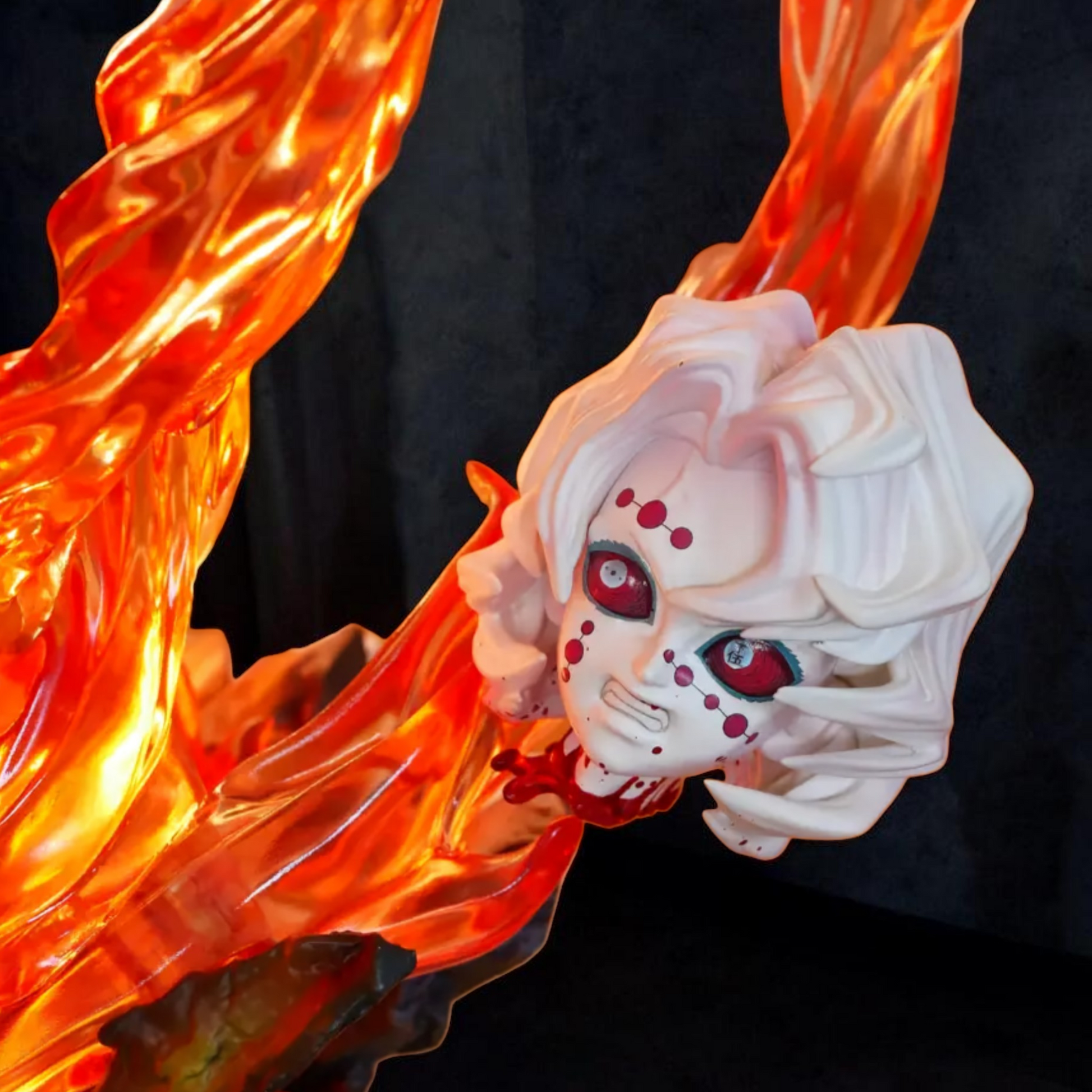 White mask with red eyes surrounded by orange flames on a black background