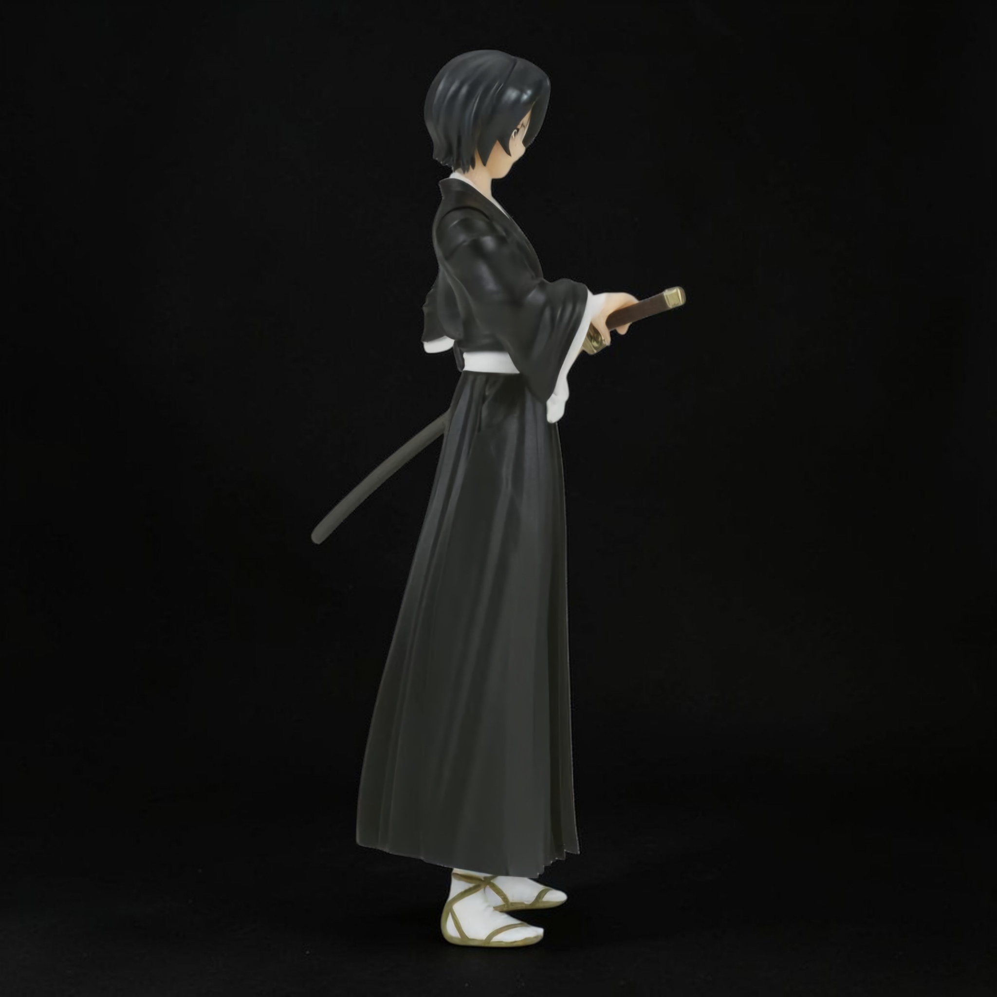 Figurine of a character in traditional attire holding a sword on a black background