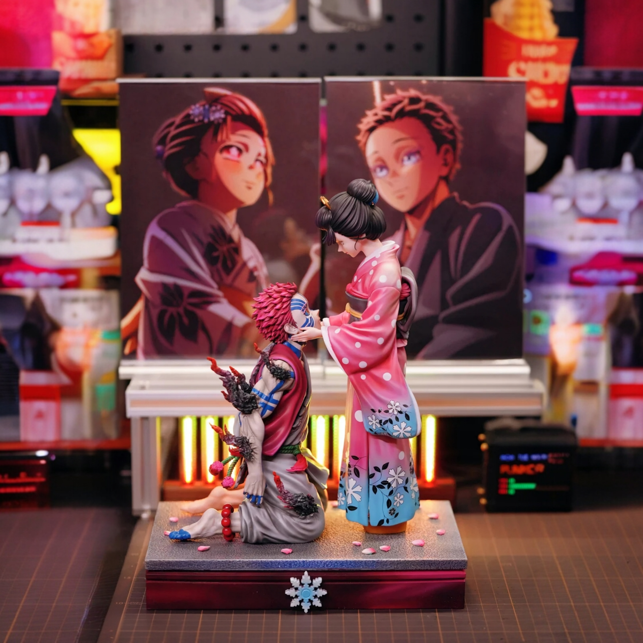 Two anime-style figurines on a stand with colorful backgrounds