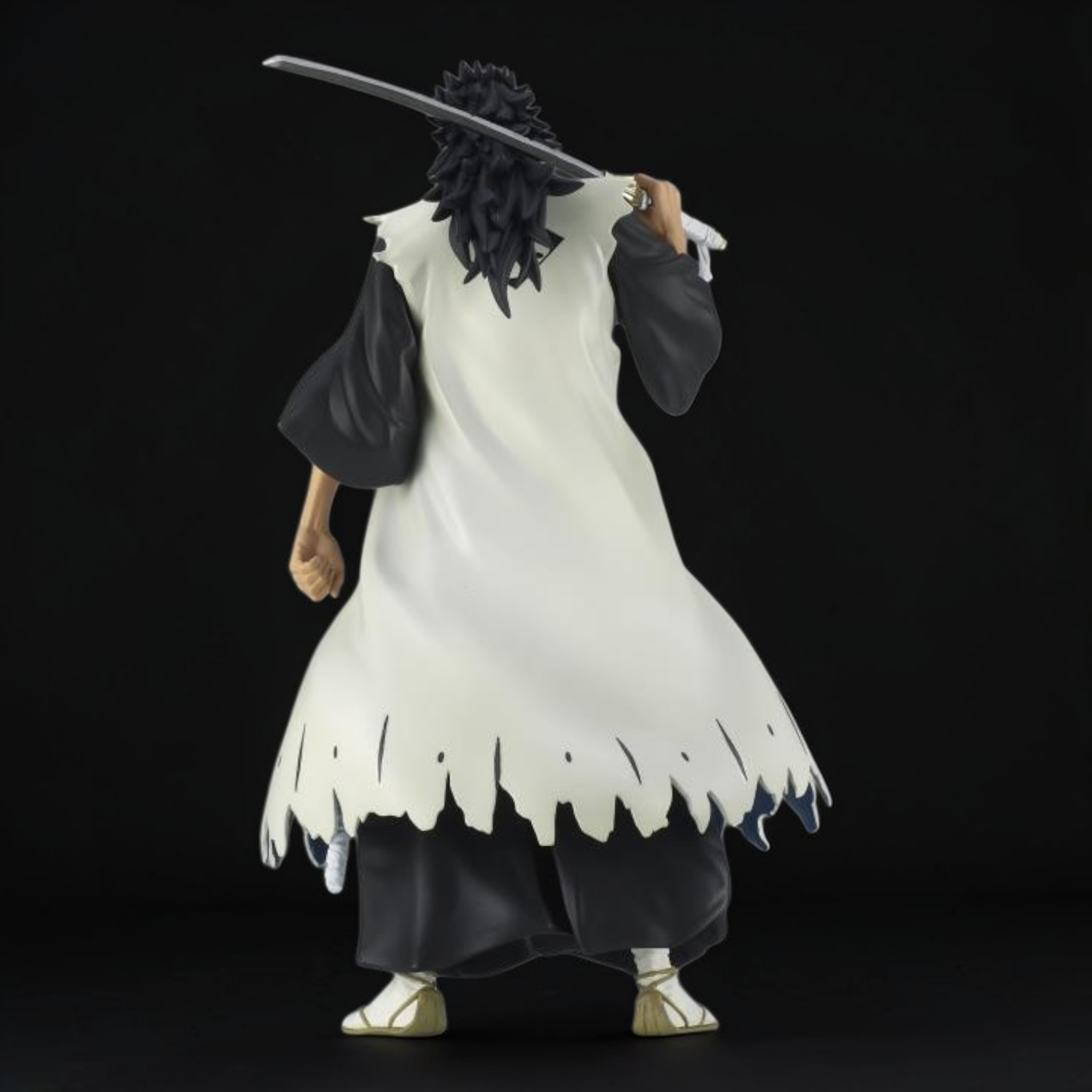 Figure of a character in a white outfit with black accents holding a sword on a black background