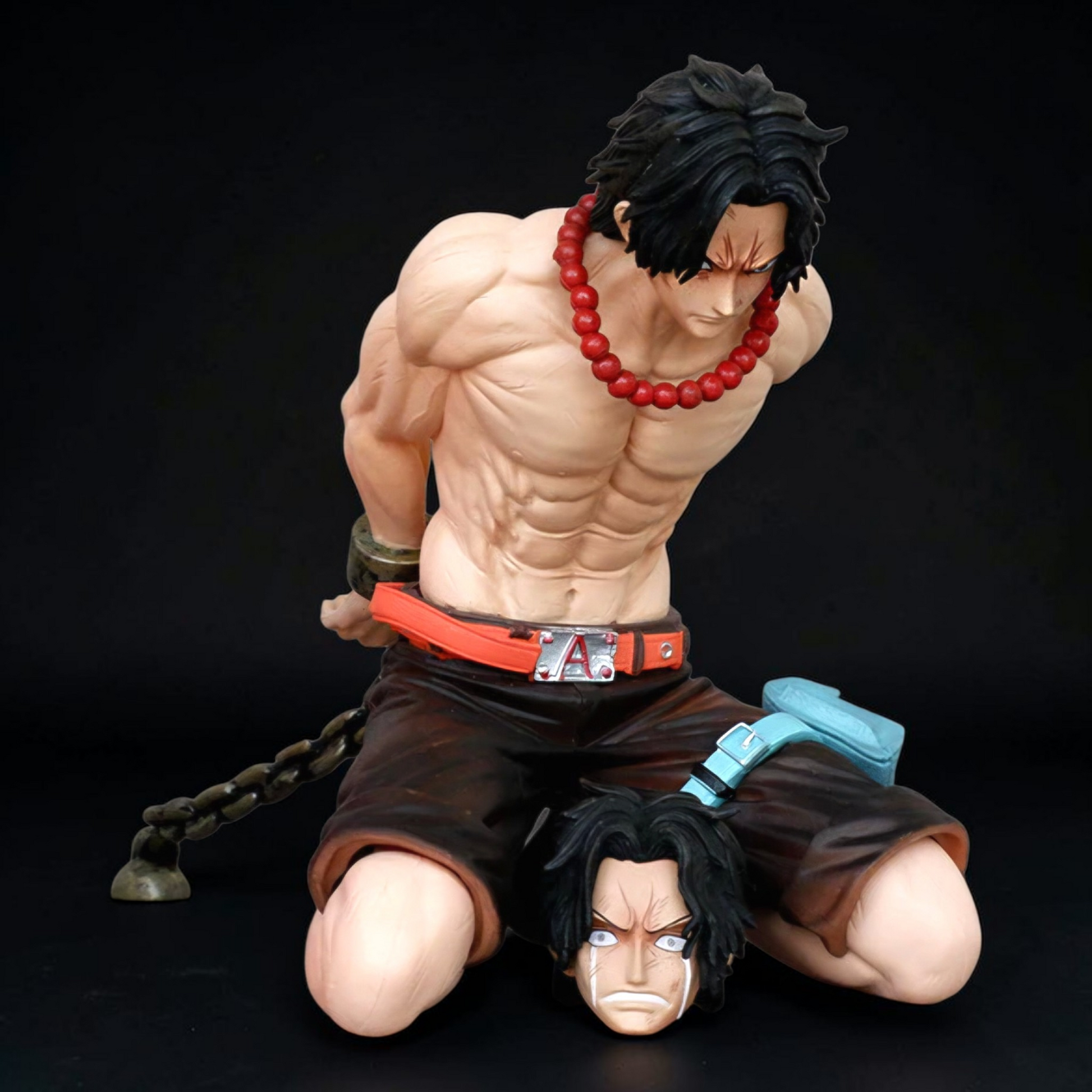 Muscular figure with red beads and black hair on a dark background